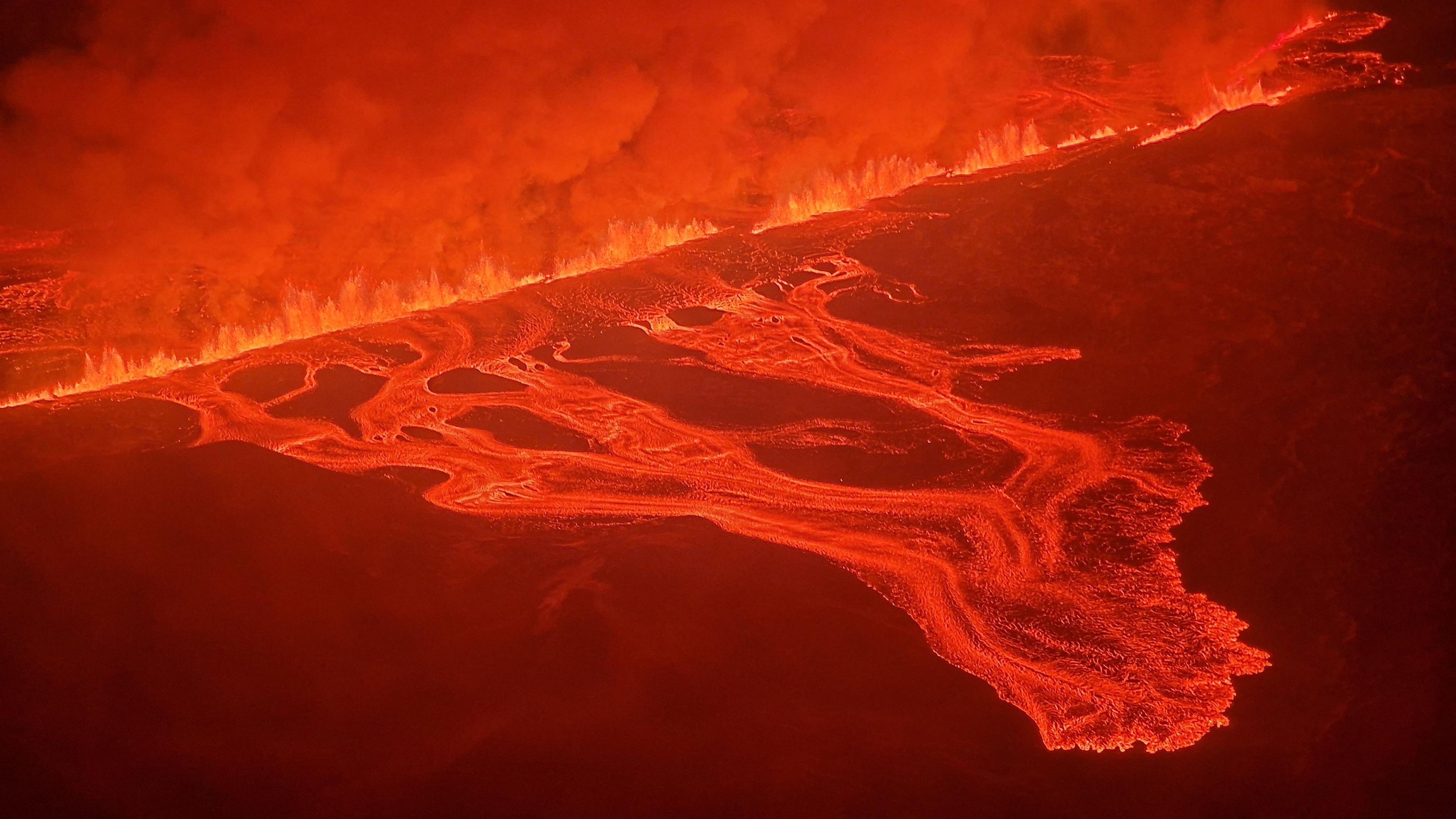 Rauch und fließende Lava, die während eines neuen Vulkanausbruchs am Rande der evakuierten Stadt Grindavik im Westen Islands aus einem neuen Spalt strömt. 