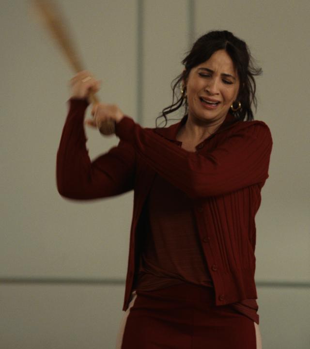 The other gAIrl – error 404 maia not found": Lisa (Chryssanthi Kavazi) steht mit hoch erhobenem Baseballschläger in einem hellen Raum in der Tanzschule.