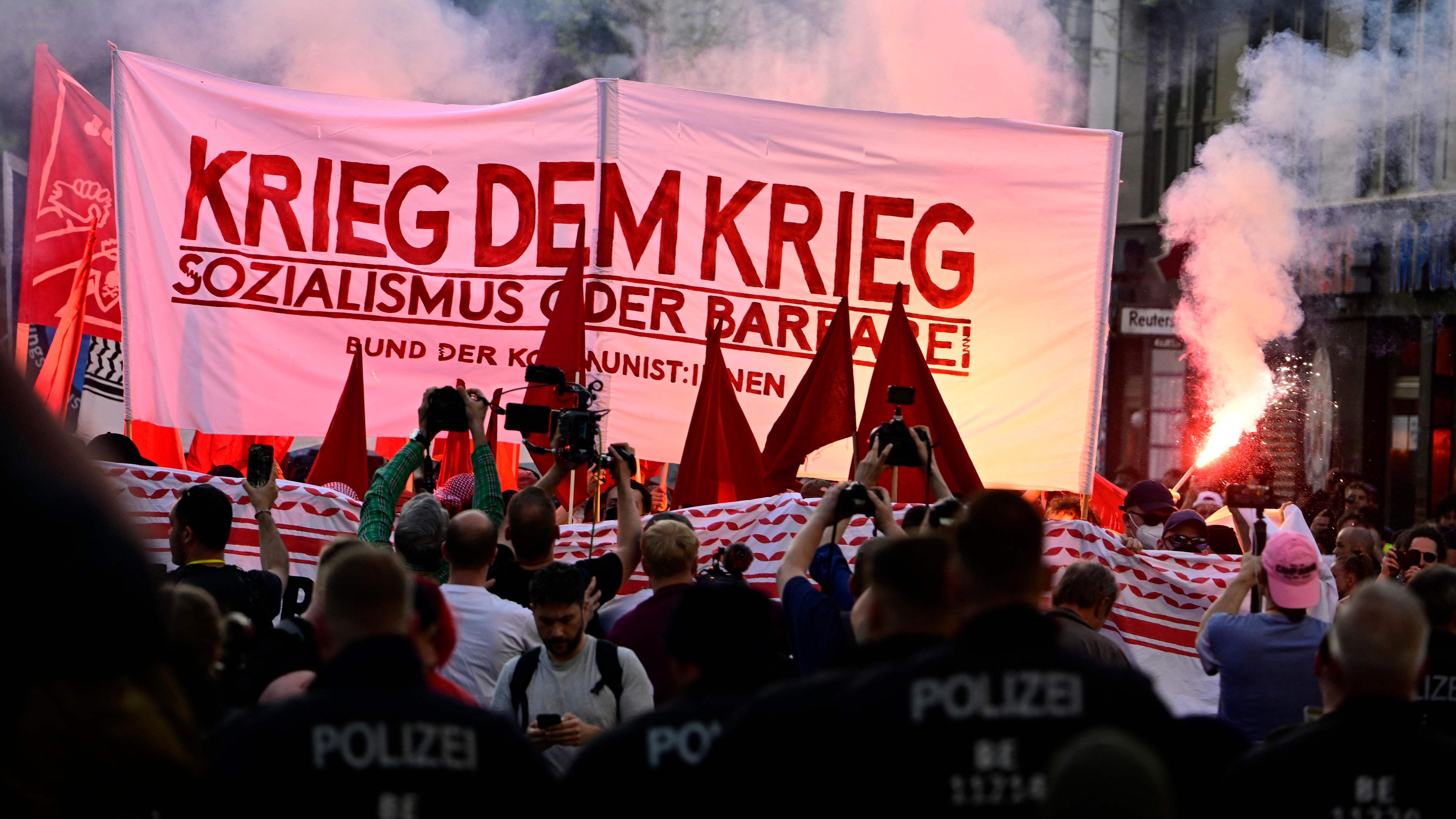 Teilnehmer der "Revolutionären 1. Mai-Demonstration" in Berlin zünden Pyrotechnik und zeigen ein ein Transparent mit der Aufschrift "Krieg dem Krieg – Sozialismus oder Barbarei"