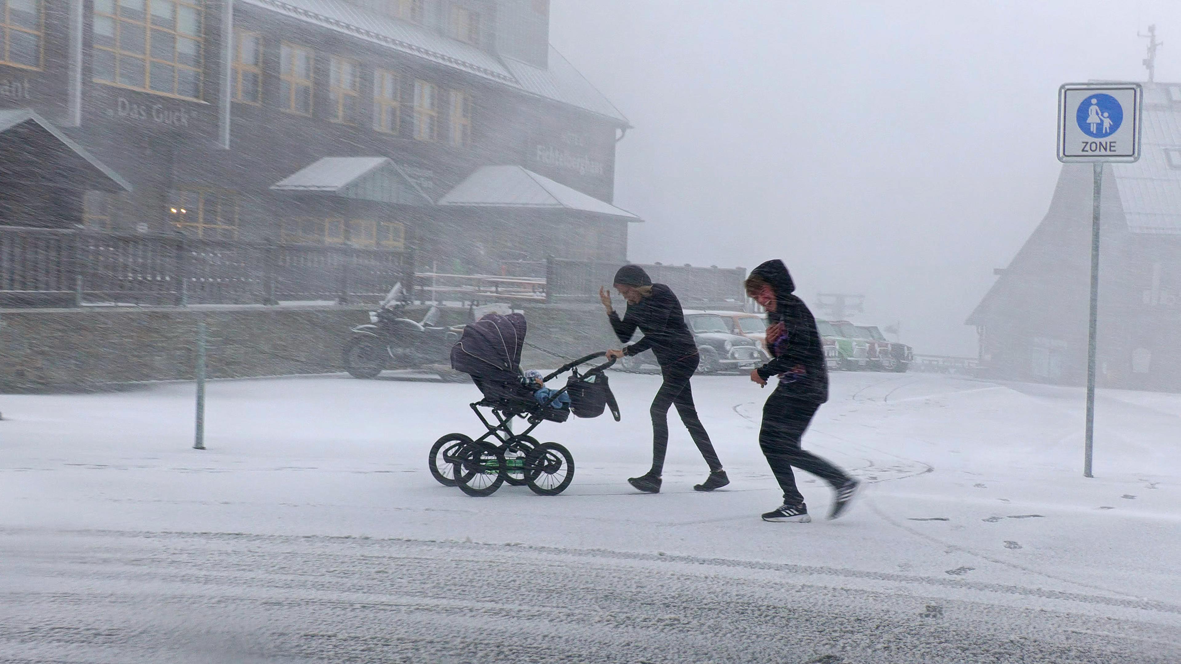  Menschen sind bei dichtem Schneetreiben auf dem Fichtelberg unterwegs.
