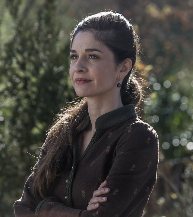 "Der Bergdoktor - Erzwungene Liebe": Kara Lambert (Anne Werner) steht im Grünen und blickt in die Ferne.