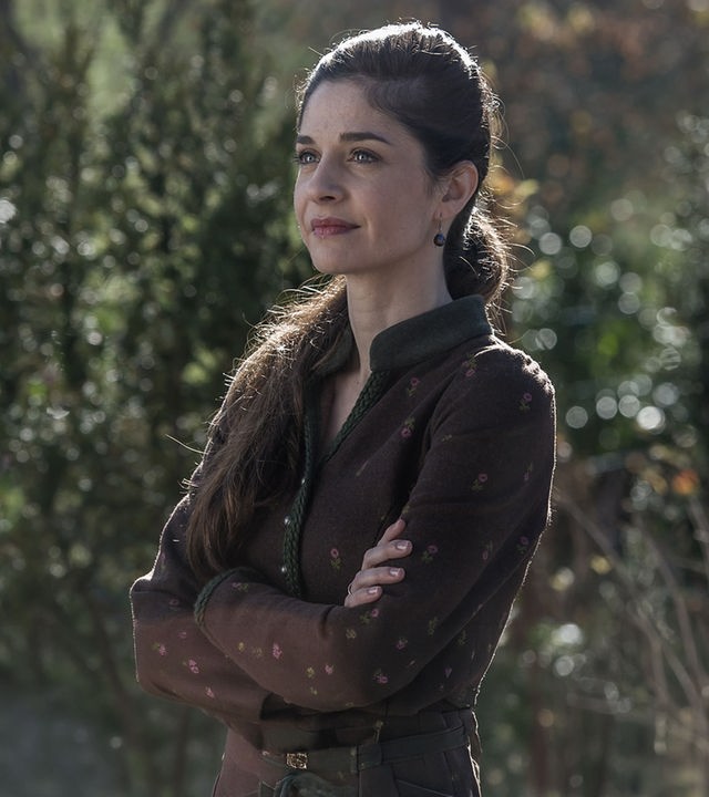 "Der Bergdoktor - Erzwungene Liebe": Kara Lambert (Anne Werner) steht im Grünen und blickt in die Ferne.