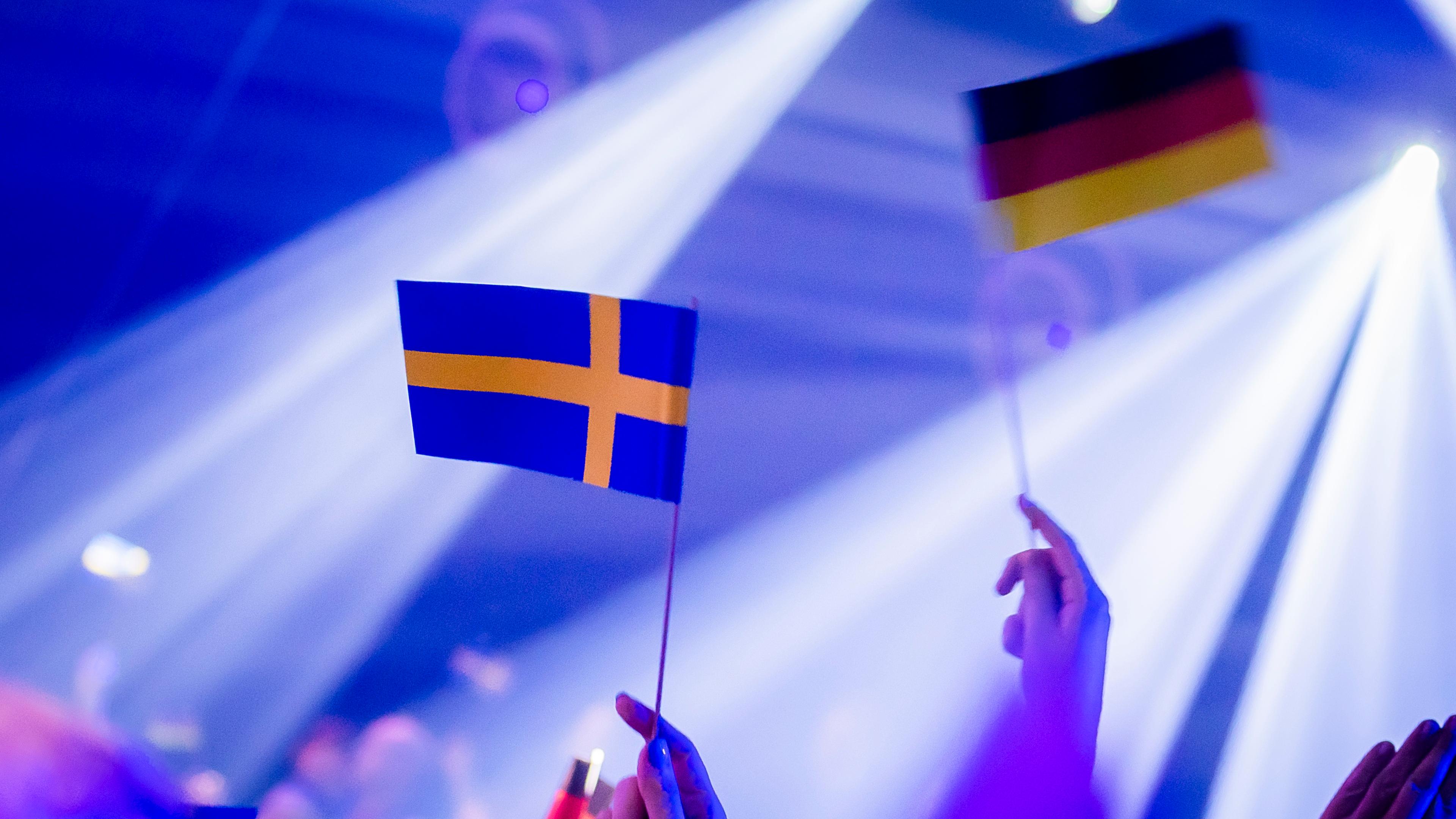 Zuschauer halten vor Beginn des Eurovision Song Contest - Das deutsche Finale 2024 die Fähnchen von Deutschland und Schweden hoch.