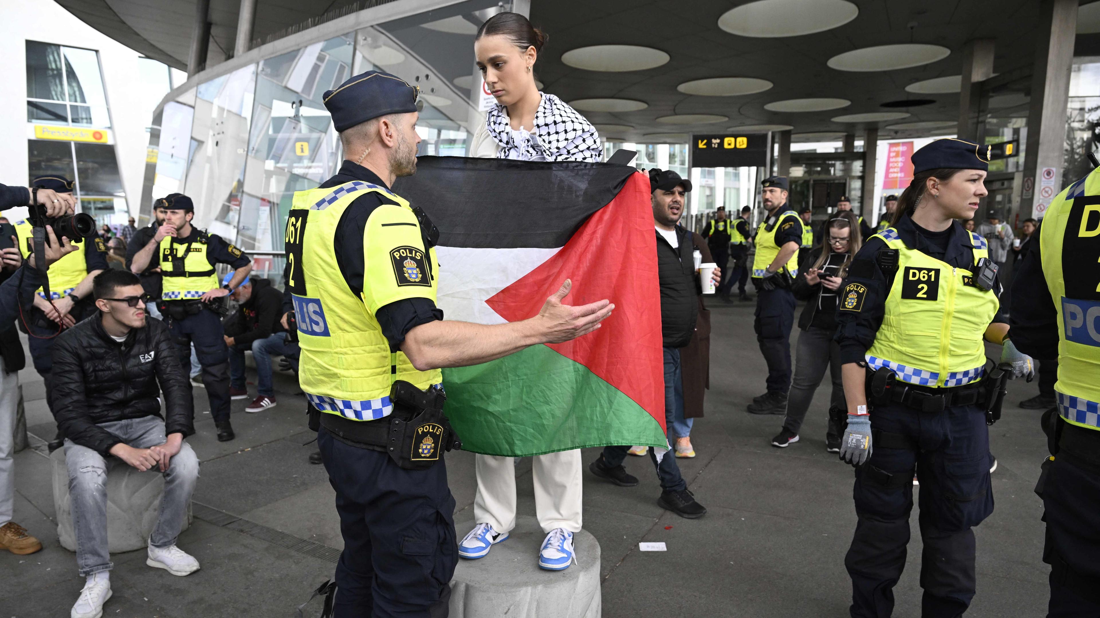Ein Polizeibeamter spricht zu einer Demonstrantin mit einer Palästinaflagge.