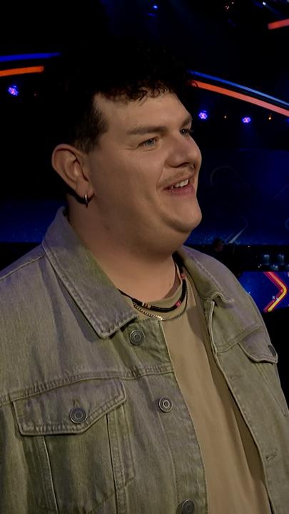 Isaak lächelt an der kamera vorbei. Im Hintergrund die Kulissen von Terra X Kids