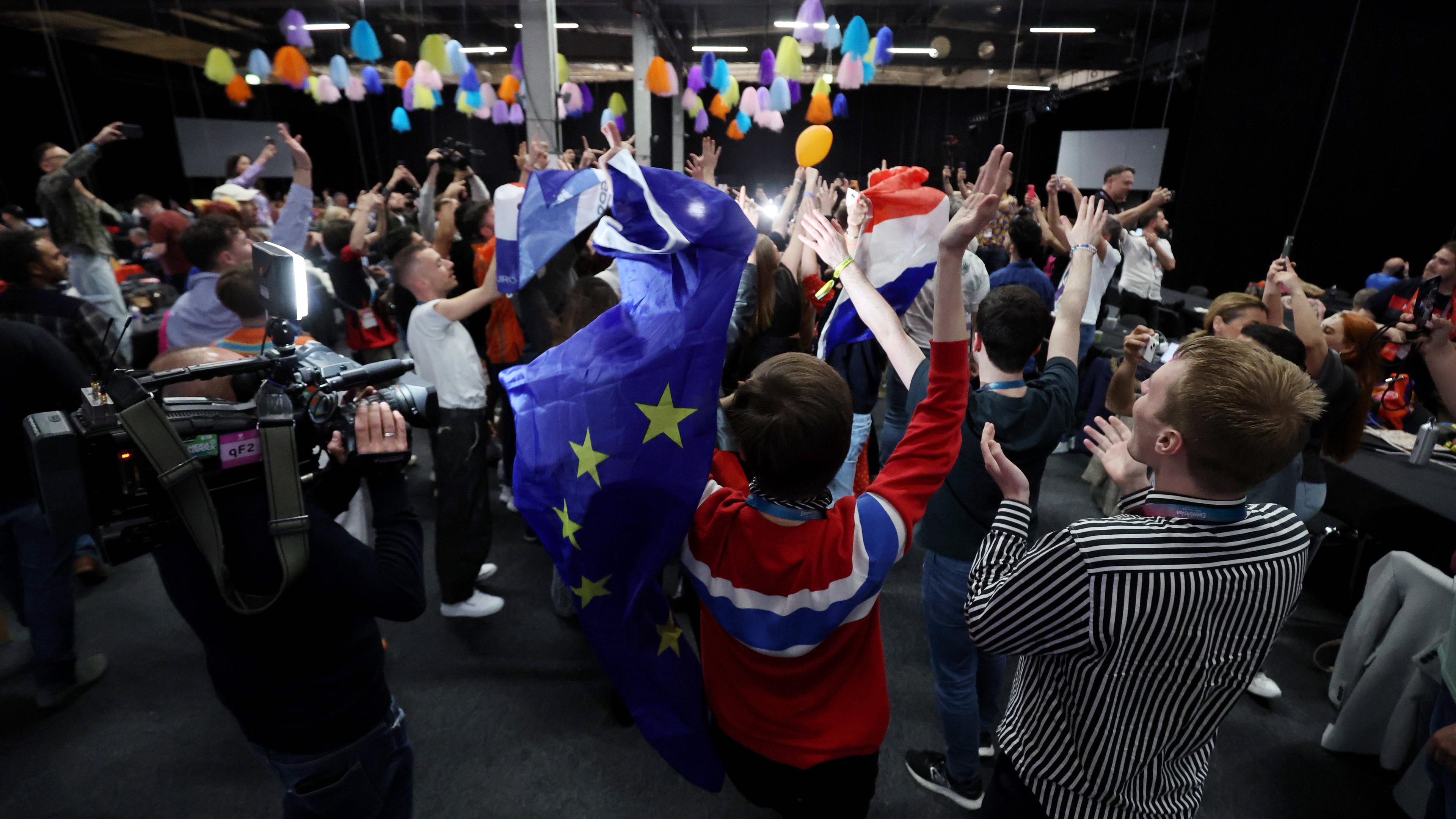 Menschen tanzen mit EU-Flagge im Medienzentrum während des zweiten Halbfinales der 68. Ausgabe des Eurovision Song Contest (ESC) in der Malmo Arena in Malmö, Schweden