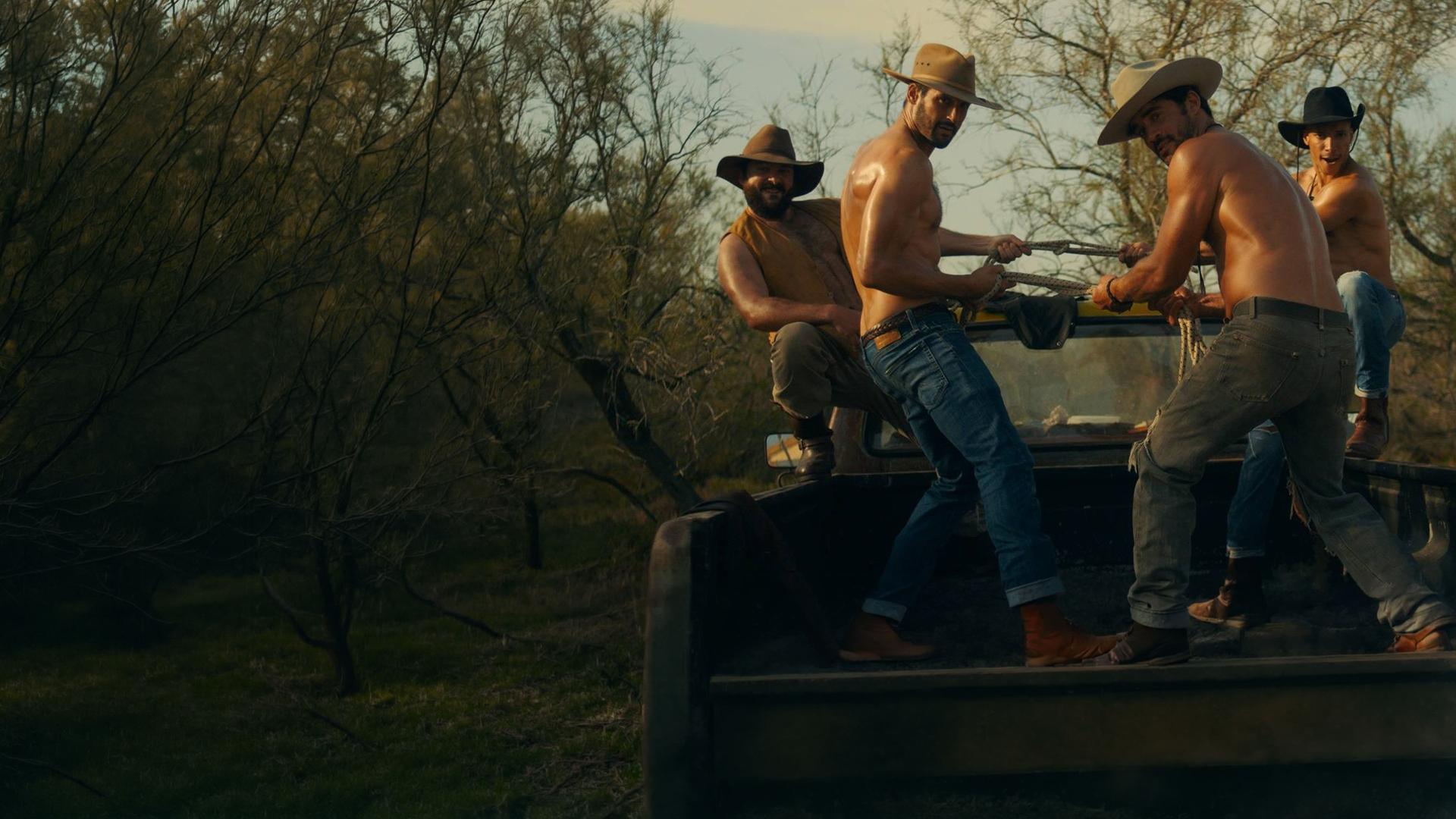 "Escort Boys - Honig ist die Zukunft": Ludo (Thibaut Evrard), Ben (Guillaume Labbé), Mathias (Simon Ehrlacher) und Zak (Corentin Fila) posieren auf der Ladefläche eines Pick-ups. Ludo und Zak hocken außen, Ben und Mathias stehen in der Mitte und halten gemeinsam ein Seil, an dem sie ziehen. Alle tragen Cowboyhüte - nur Ludo trägt zusätzlich eine offene gelbe Weste, die anderen sind oberkörperfrei.