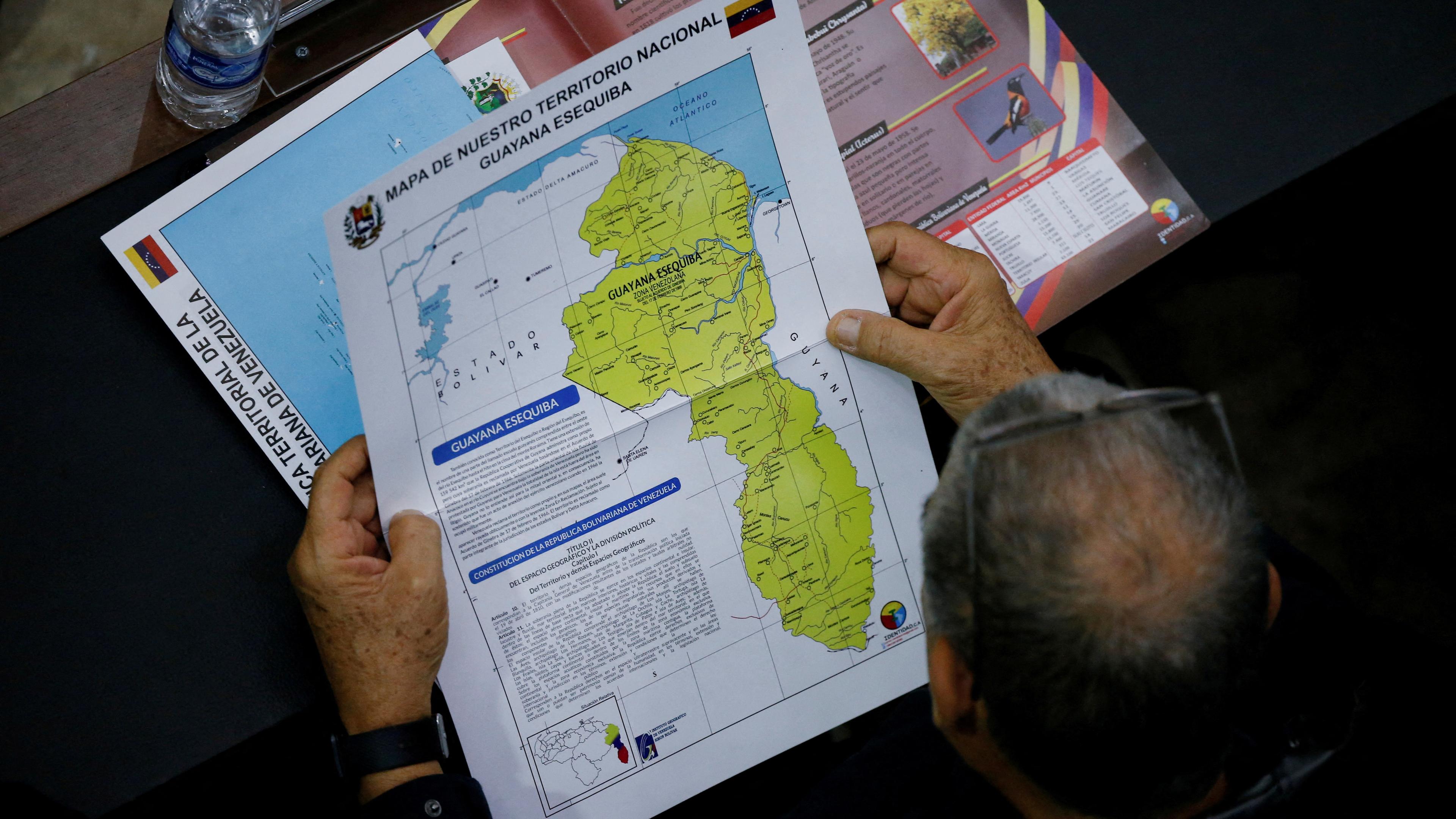 Ein Mitglied der Nationalversammlung hält eine Karte in der Hand, auf der die umstrittene Esequibo-Region als Teil Venezuelas zu sehen ist