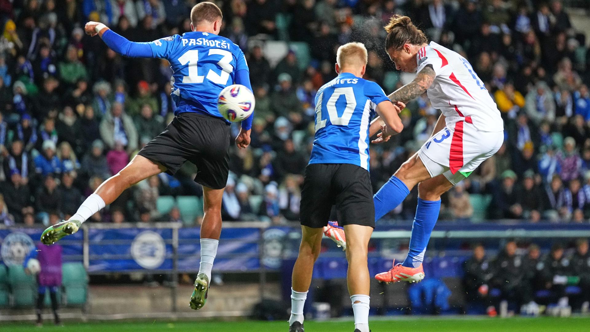 Riccardo Calafiori beim Kopfball. Zwei Spieler Estlands springen ebenfalls hoch