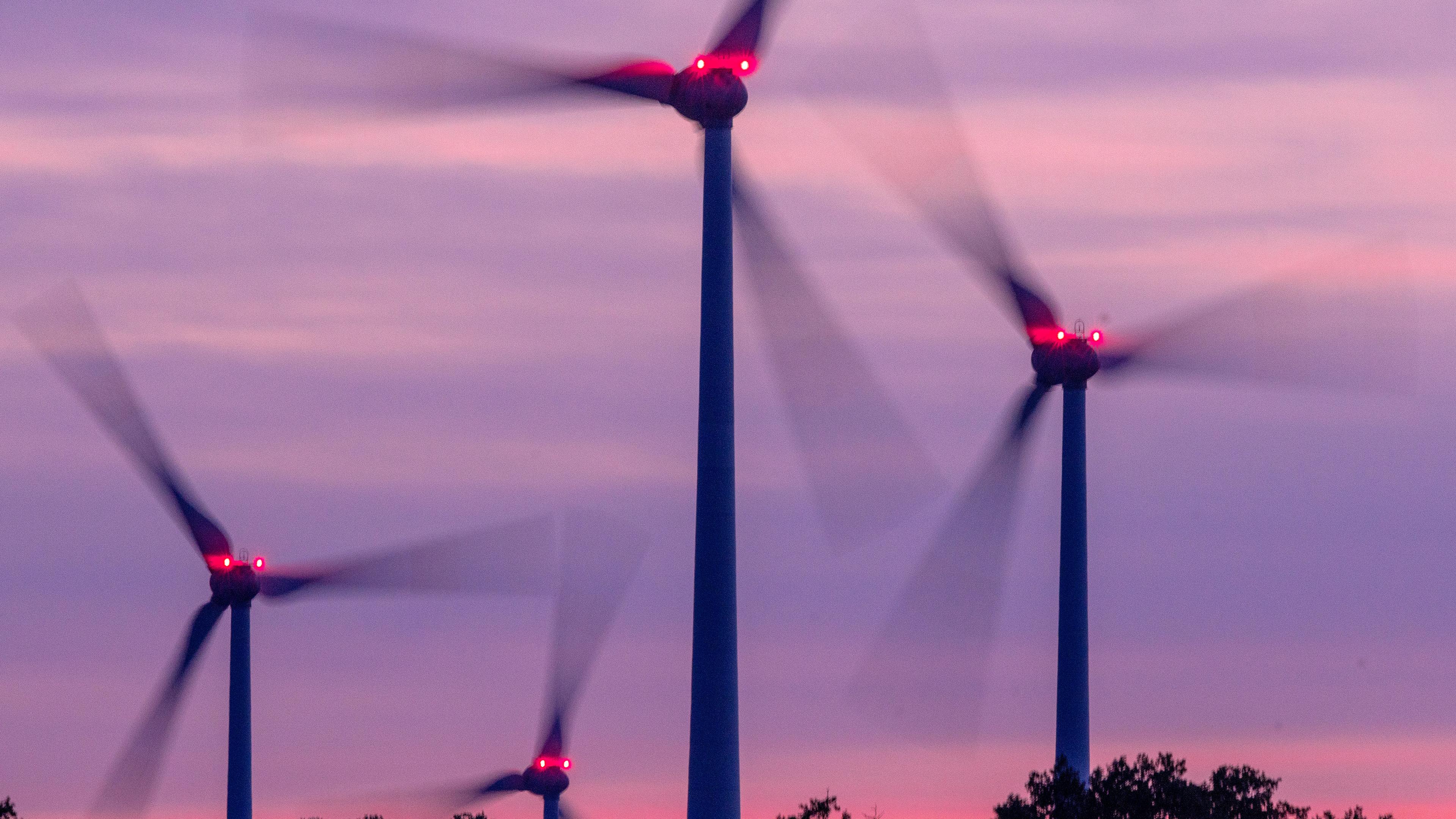 Mit Signallampen beleuchtete Windräder drehen sich nach Sonnenuntergang in einem Windpark in Deutschland.