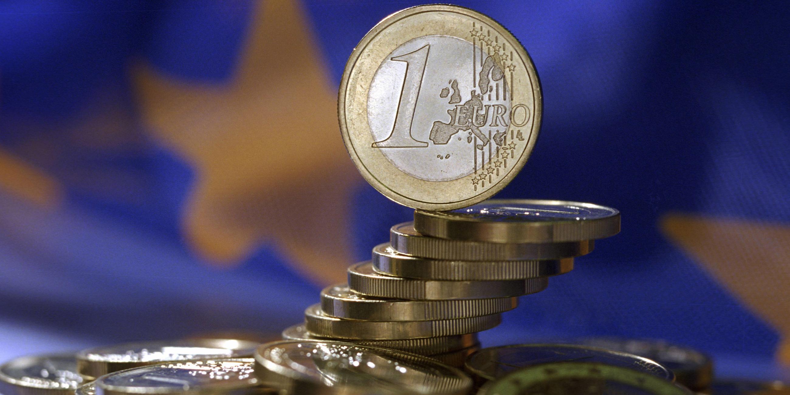 Euro-Münzen vor EU-Flagge