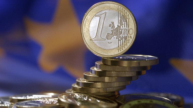 Euro-Münzen vor EU-Flagge