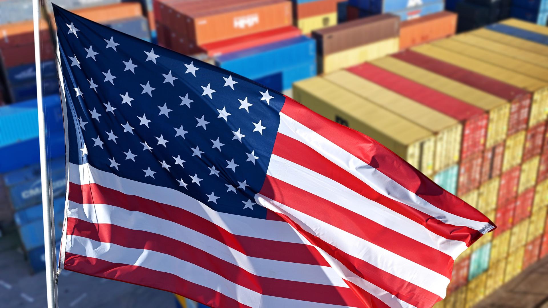 Eine US-Flgge vor Schiffsconatinern.