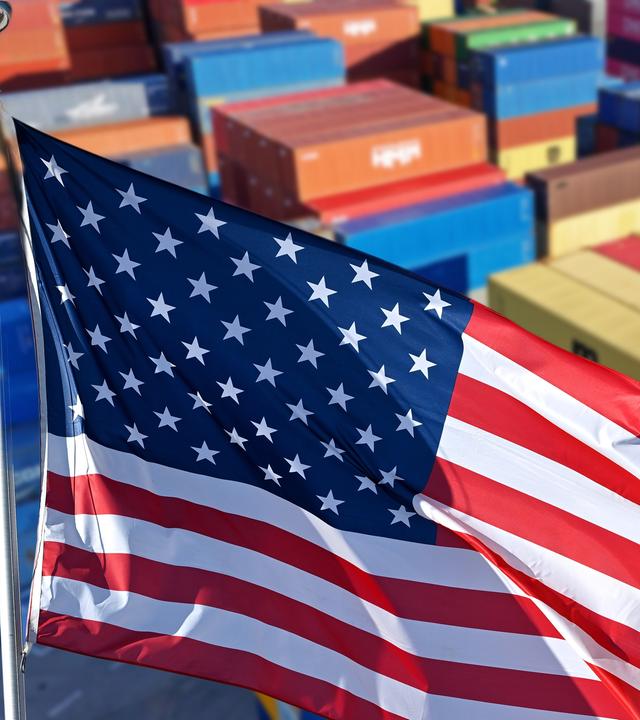 Eine US-Flgge vor Schiffsconatinern.