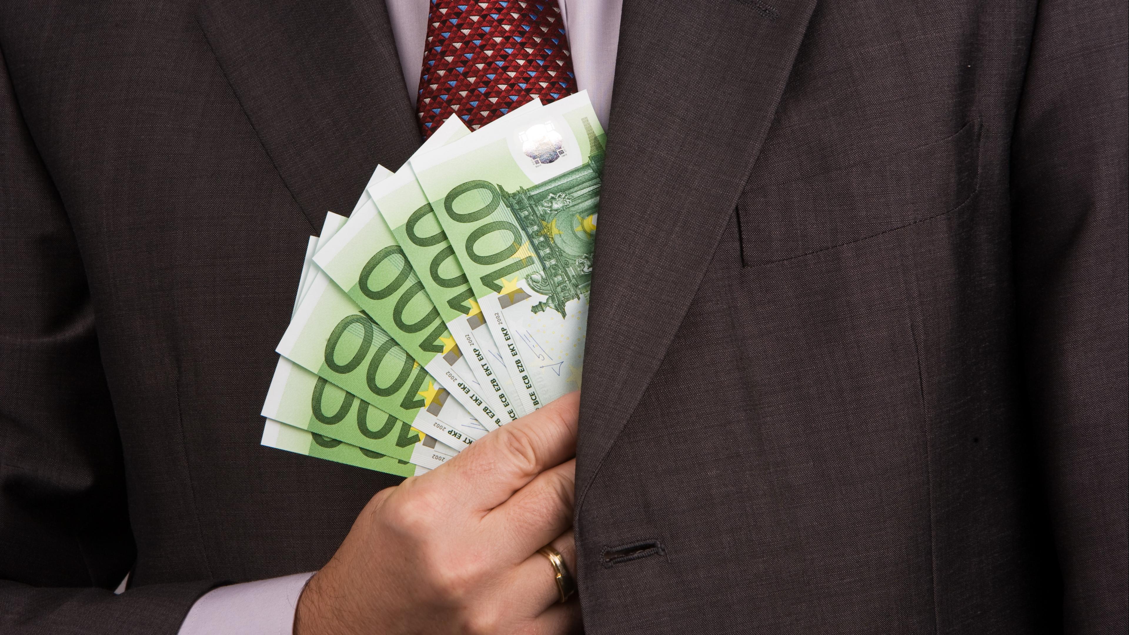 Symbolbild: Mann holt ein Bündel Euro-Geldscheine aus seinem Jackett 