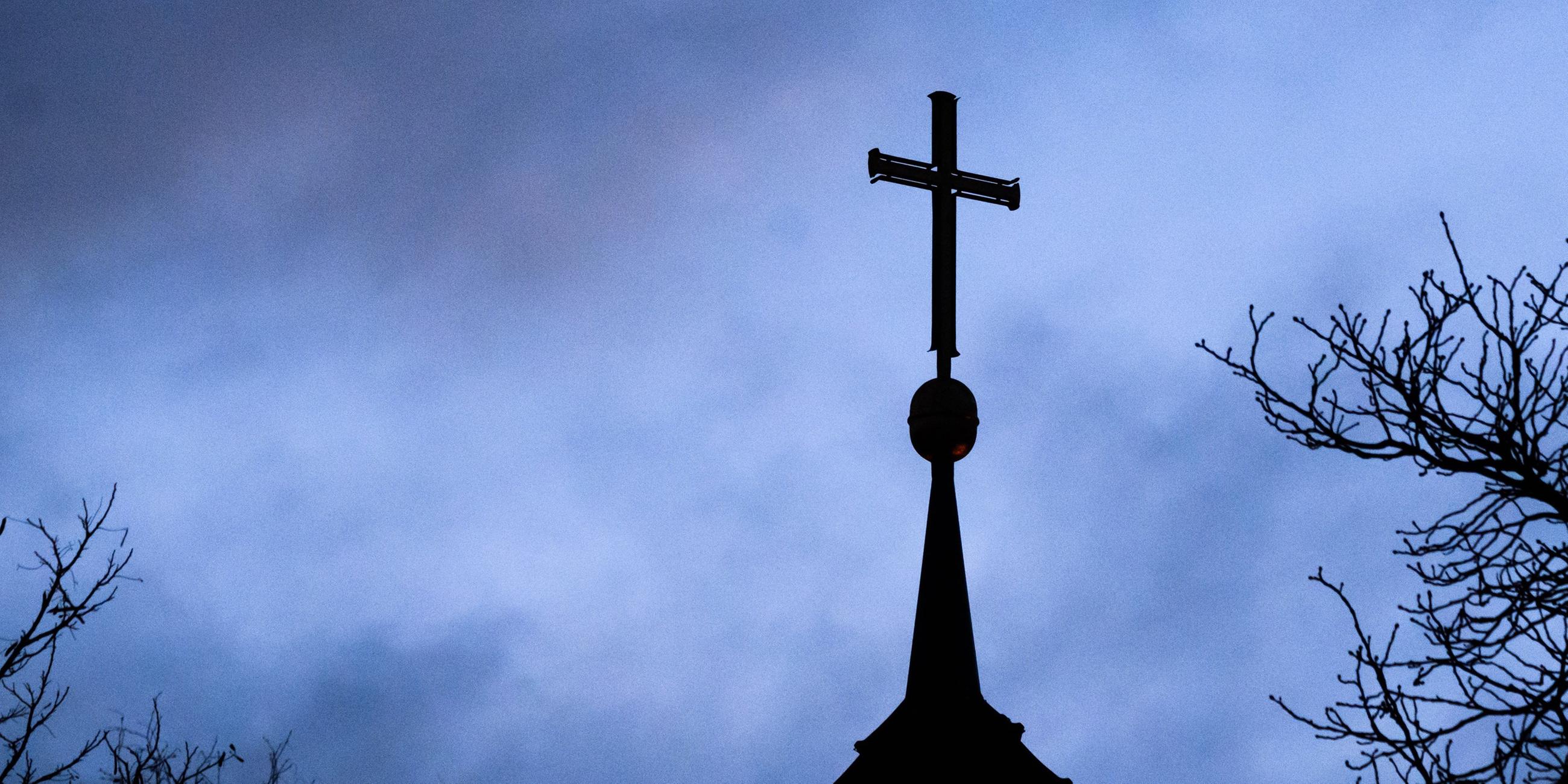 Dunkle Wolken ziehen über das Kreuz auf einer evangelischen Kirche