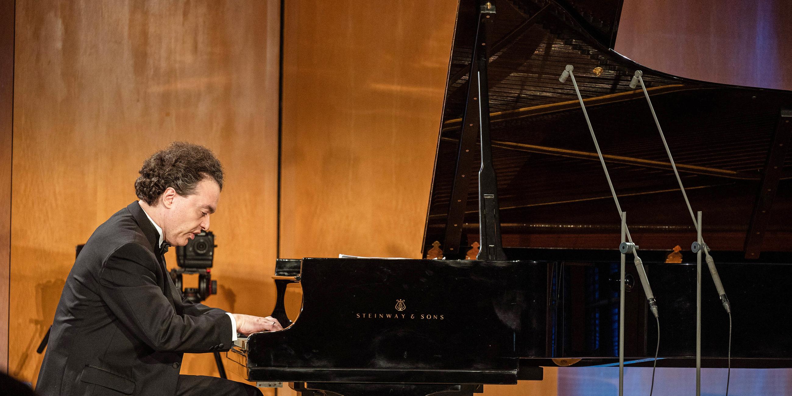 Der russische Pianist Evgeny Kissin sitzt an einem Flügel auf einer Bühne und spielt.