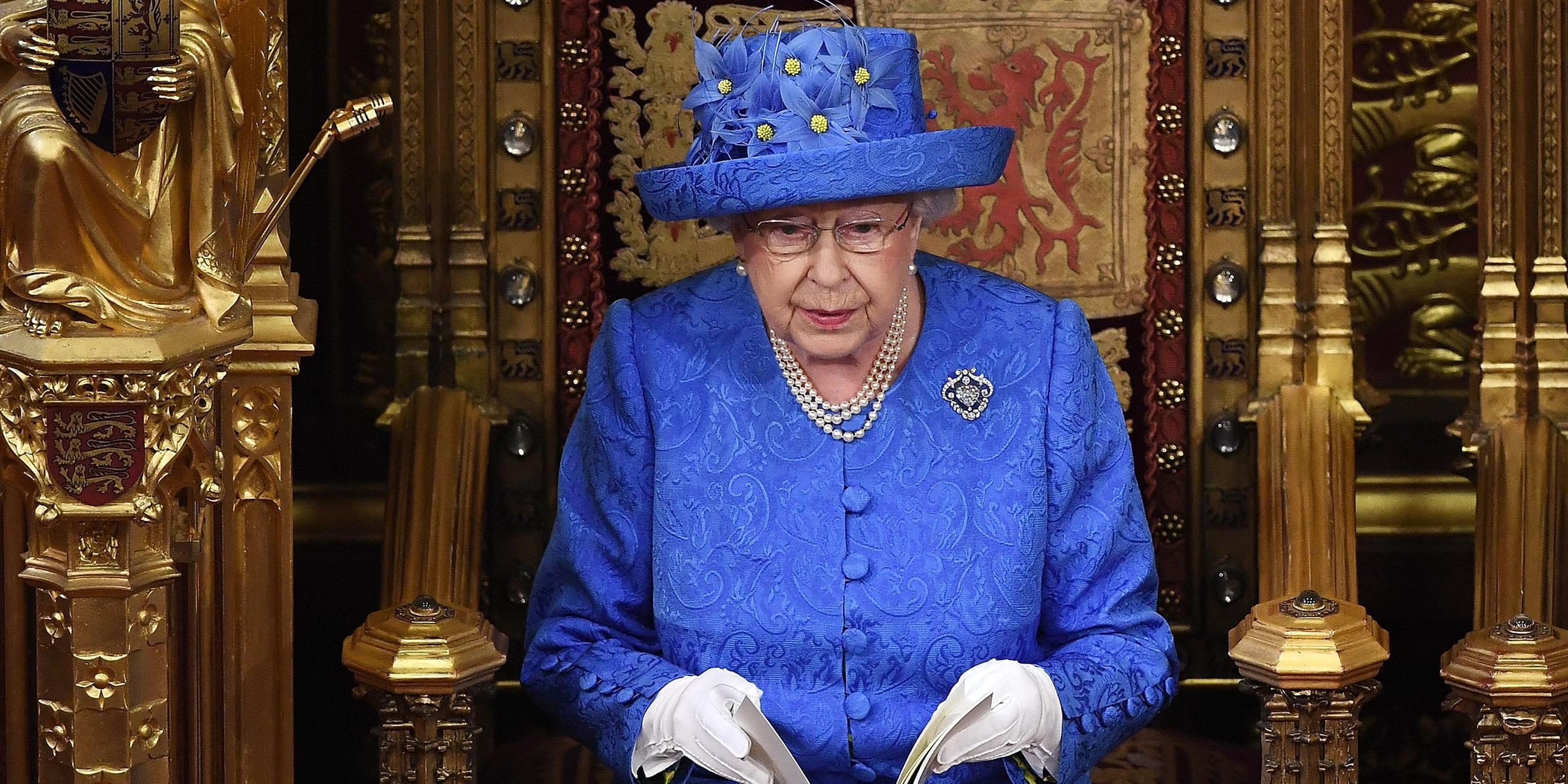 Das Bild zeigt Queen Elizabeth II mit einem blauen Hut mit gelben Blüten