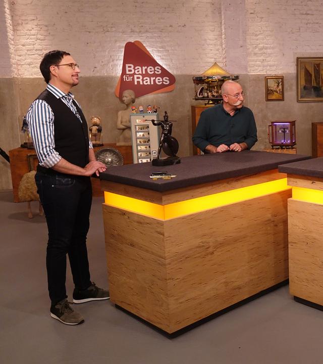 Experte Colmar Schulte-Goltz (links) hat eine Bronzefigur eines Speerwerfers vor sich auf dem Tisch stehen. Er und Horst Lichter (Mitte) schauen das Verkäuferpaar (rechts) an.