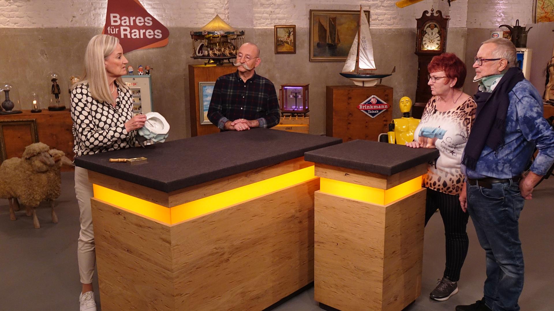 Expertin Dr. Friederike Werner (links) hat ein Objekt zur Begutachtung in der Hand. Sie und Horst Lichter (Mitte) schauen das Verkäuferpaar (rechts) an.