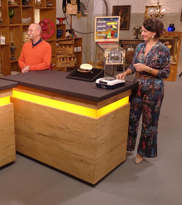 Expertin Wendela Horz (rechts) hat Schmuck und eine Waage vor sich auf dem Tisch stehen. Sie und Horst Lichter (Mitte) schauen die Verkäuferin (links) an.