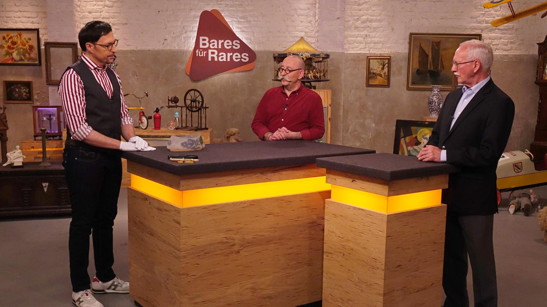 Colmar und Horst stehen mit einem potenziellen Verkäufer am Expertentisch.