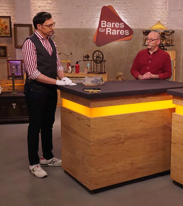 Colmar und Horst stehen mit einem potenziellen Verkäufer am Expertentisch.