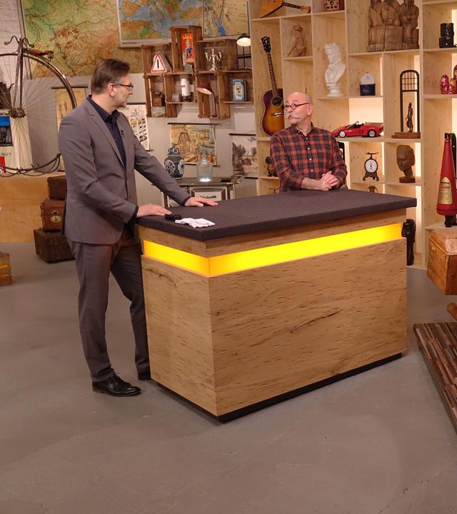 Experte Detlev Kümmel begutachtet ein Motorrad aus Holz. Neben ihm stehen Horst Lichter und der Verkäufer des Objekts.