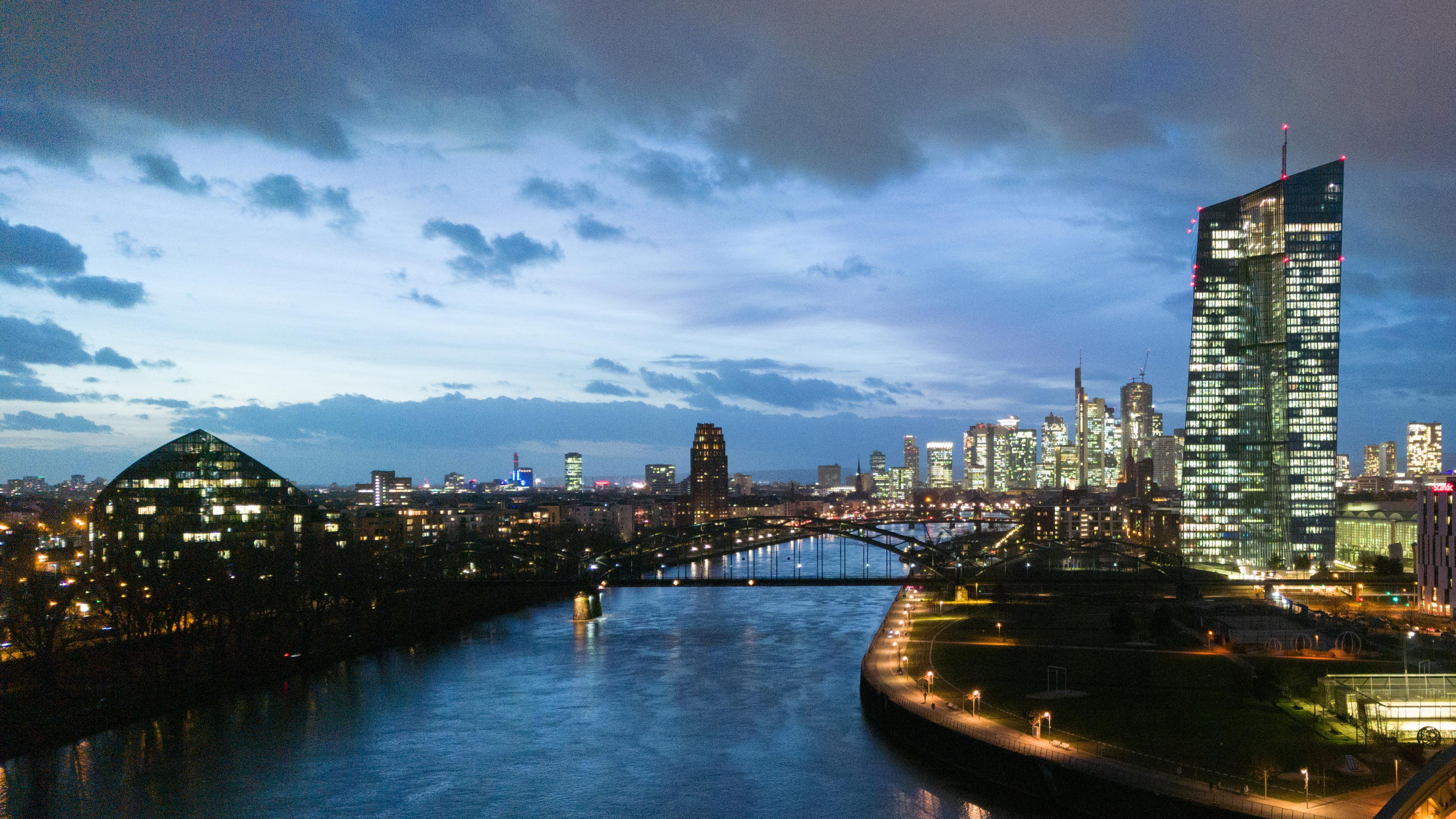 Hessen, Frankfurt/Main: Die EZB leuchtet vor der Hochhauskulisse der Innenstadt von Frankfurt am Main.
