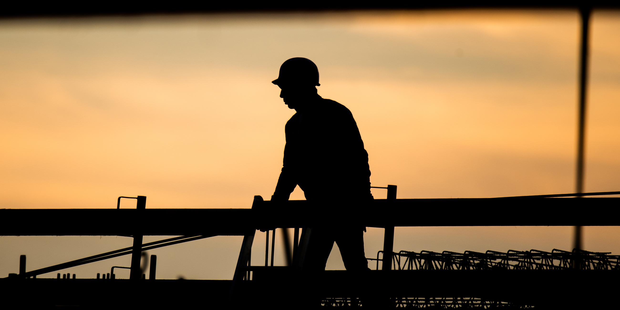 Silhouette eines Bauarbeiters vor Sonnenuntergang