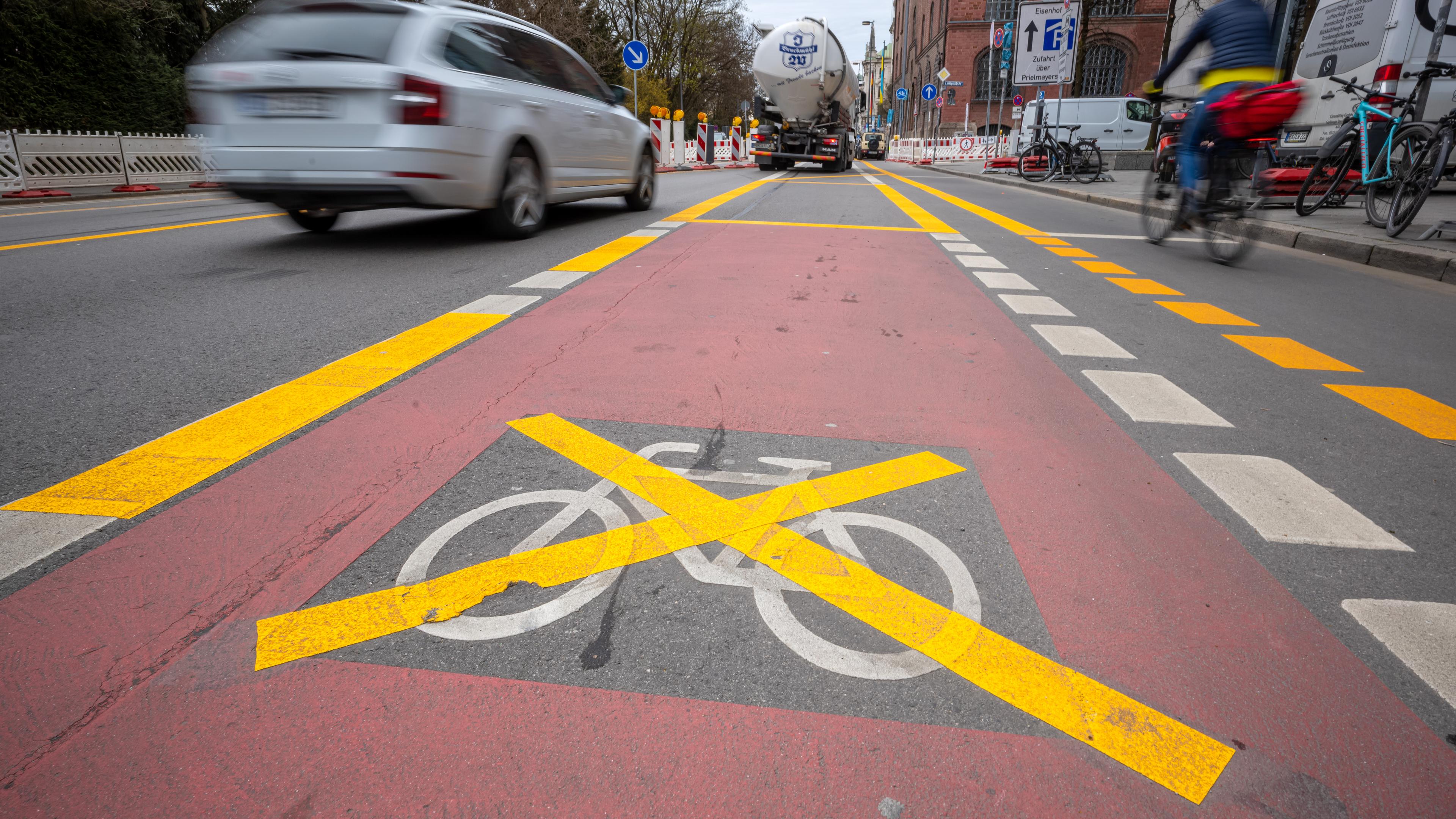 Ein Fahrradsymbol auf einem Fahrradweg ist durch gelbe Baustellenstreifen durchgestrichen.