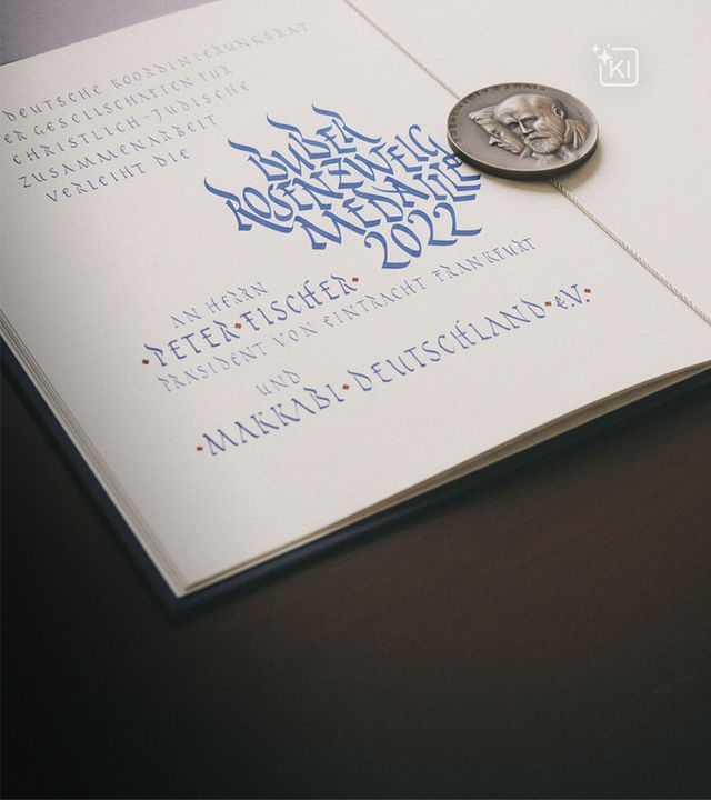 Eine aufgeschlagene Buchseite, auf der eine silberne Medaille liegt.