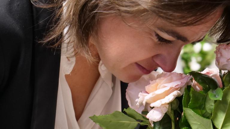 Hortense Harang riecht an einer hellrosa Rose.