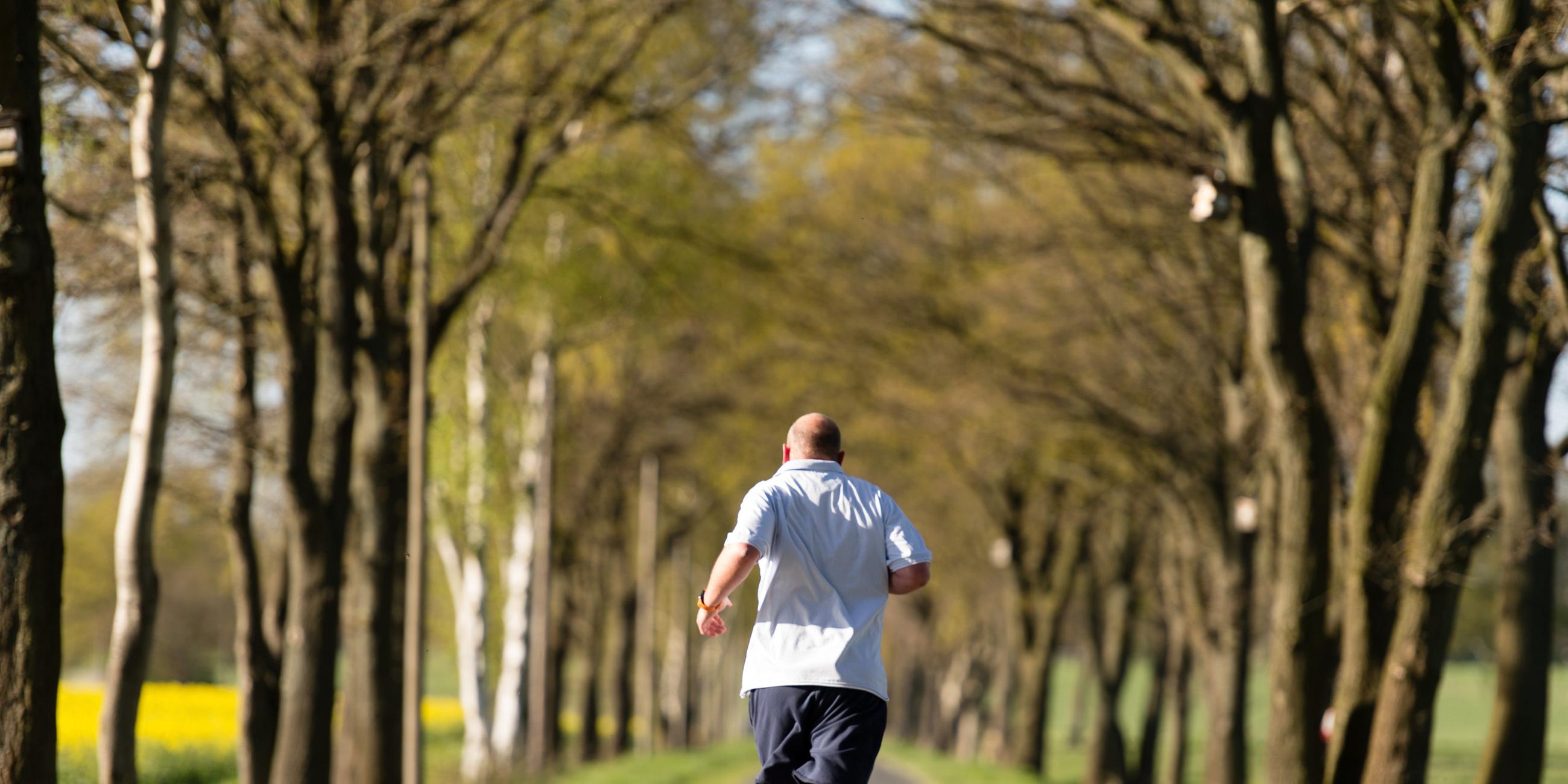 Ein Mann joggt auf einer Landstraße.