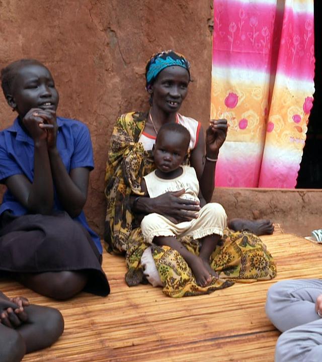 Dunja Hayali mit einer Familie in einem Flüchtlingslager im Südsudan