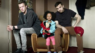 Familie Braun": Kai (Vincent Krüger) und Thomas (Edin Hasanovic) sitzen auf den Lehnen eines Sessels. Zwischen ihnen in der Mitte sitzt Lara (Nomie Laine Tucker).