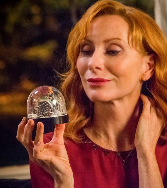 Gundula (Andrea Sawatzki) lächelt verliebt in eine Schneekugel, die sie in der Hand hält.