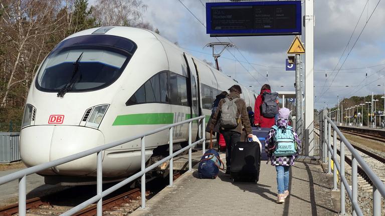 Reisende und ICE T im Bahnhof