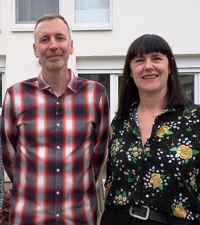 Familie Robertz, bestehend aus Vater, Mutter und Tochter, steht vor einer weißen Hauswand und lächelt in die Kamera.