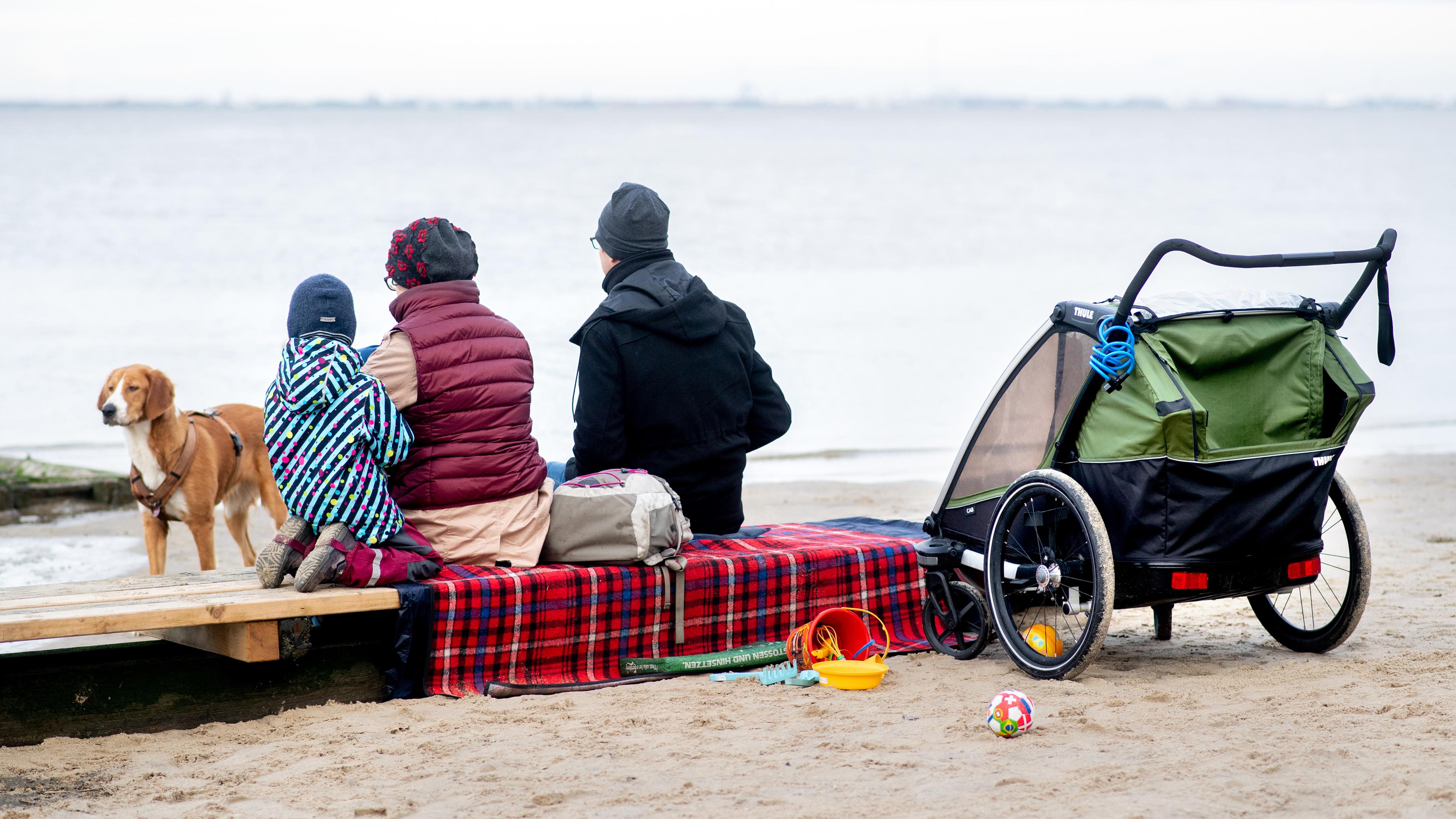 Niedersachsen, Dangast: Eine Familie sitzt bei trübem Wetter auf einer Bank am Strand. 