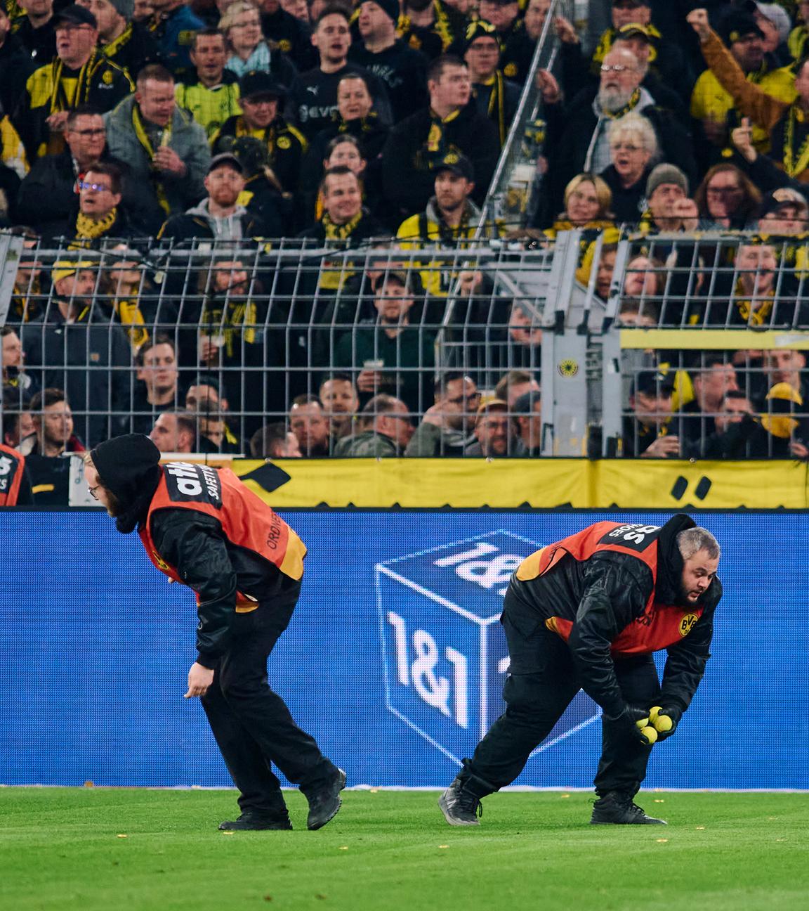 Stadionmitarbeiter sammeln Tennisbälle ein, die Dortmunds Fans auf das Spielfeld geworfen haben, um gegen Investoren in der DFL zu protestieren.