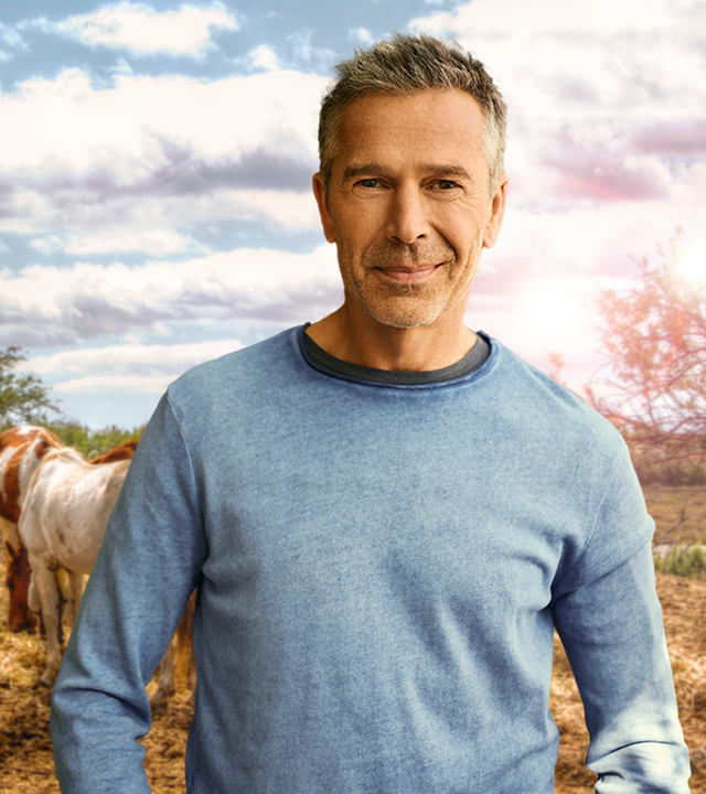 Dirk Steffens auf einem Feld vor Pferden.