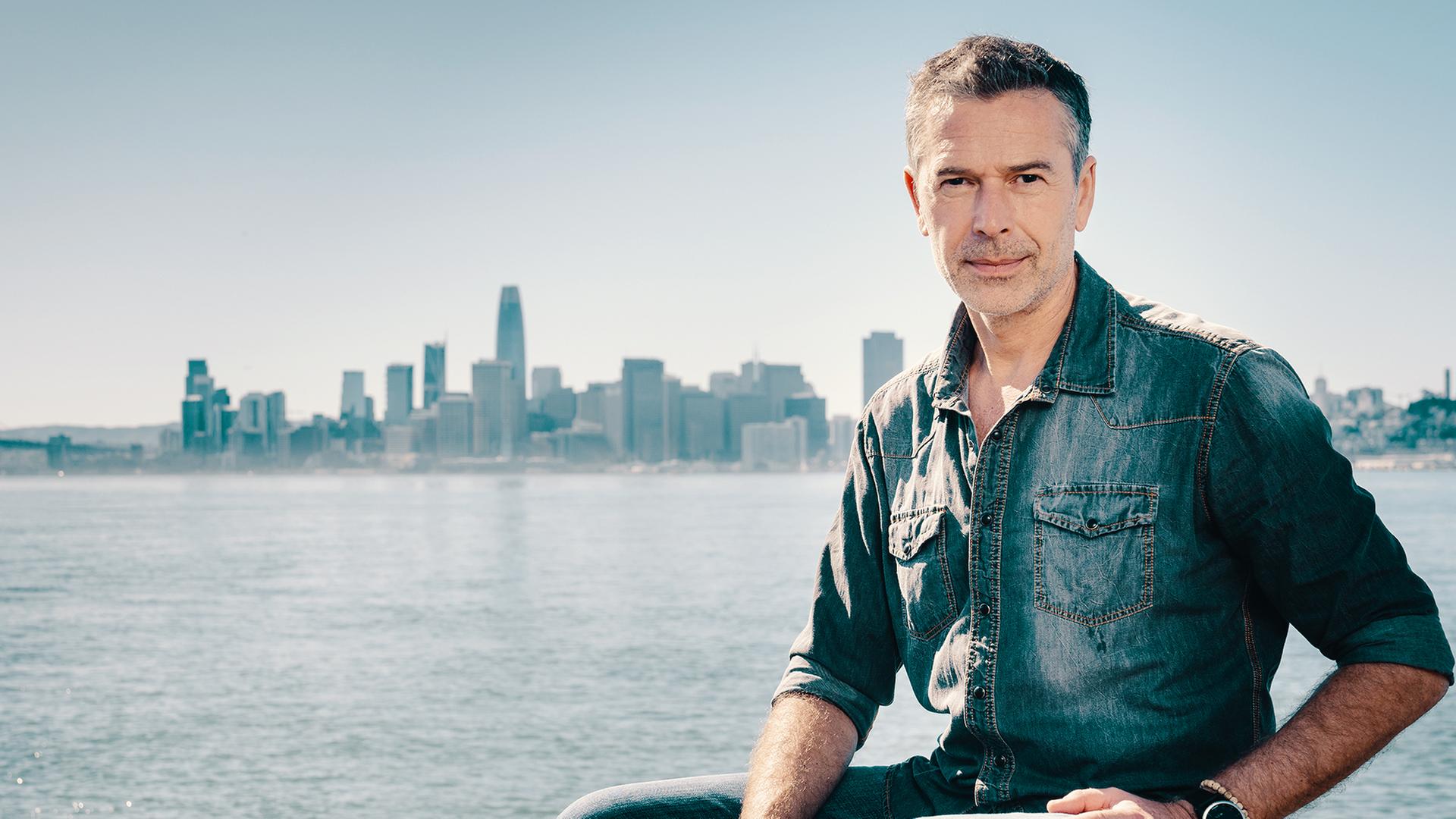 Dirk Steffens, rechts, vor einer Skyline