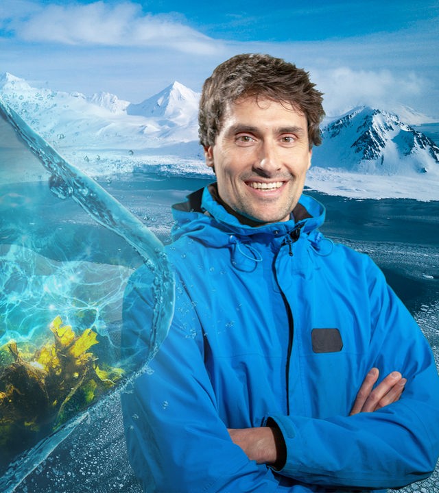 Forschungstaucher Uli Kunz trägt eine blaue Jacke, hinter ihm liegen Gletscher und Eis.
