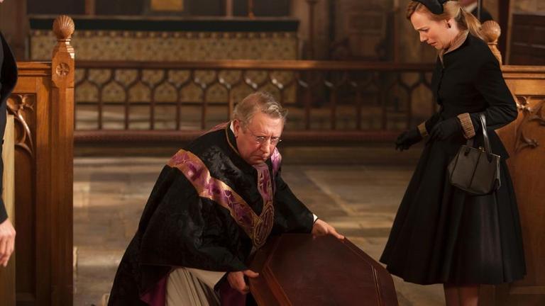 Picture shows: Father Brown (MARK WILLIAMS) hears a muffled shout from inside the coffin. He stops the pallbearers. 