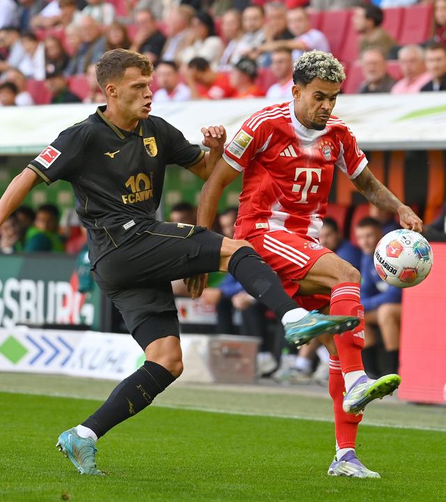 Die Spieler von FC Augsburg und FC Bayern München kämpfen.