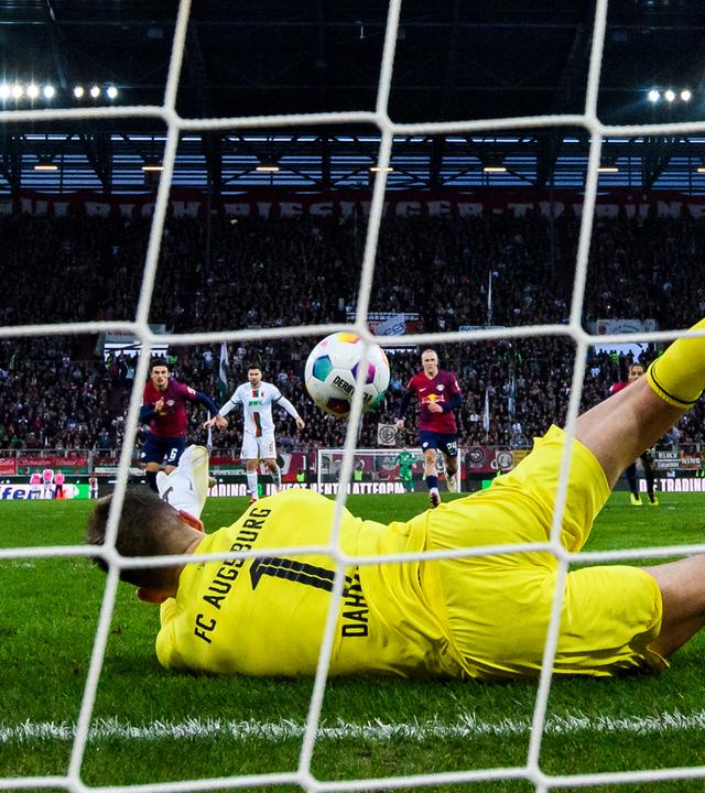Augsburgs Torwart Finn Dahmen (M) hält den Elfmeter von Leipzigs Lois Openda (3.v.r). 