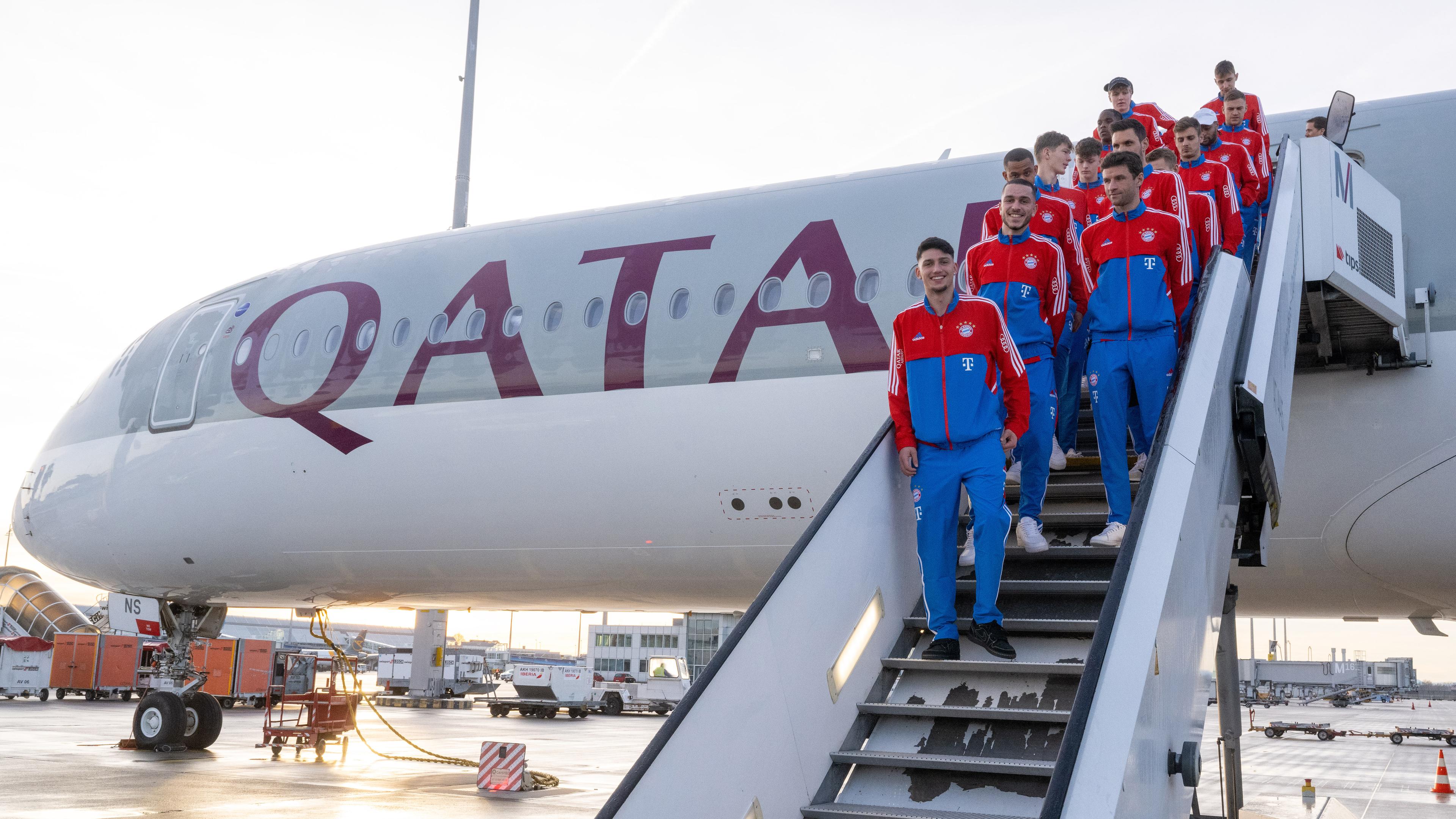 Die Spieler des deutschen Fußball-Bundesligisten FC Bayern München stehen auf der Treppe eines Flugzeugs der Fluglinie Qatar Airways, aufgenommen am 06.01.2023