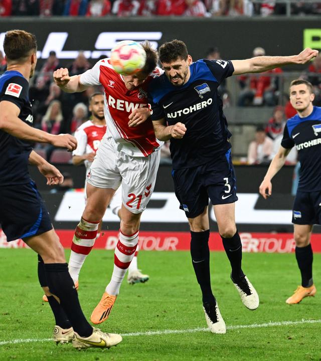 12.05.2023, Nordrhein-Westfalen, Köln: Fußball: Bundesliga, 1. FC Köln - Hertha BSC, 32. Spieltag, RheinEnergieStadion. Kölns Steffen Tigges (2.v.l) kommt vor Herthas Agustin Rogel (2.v.r.) zum Kopfball.