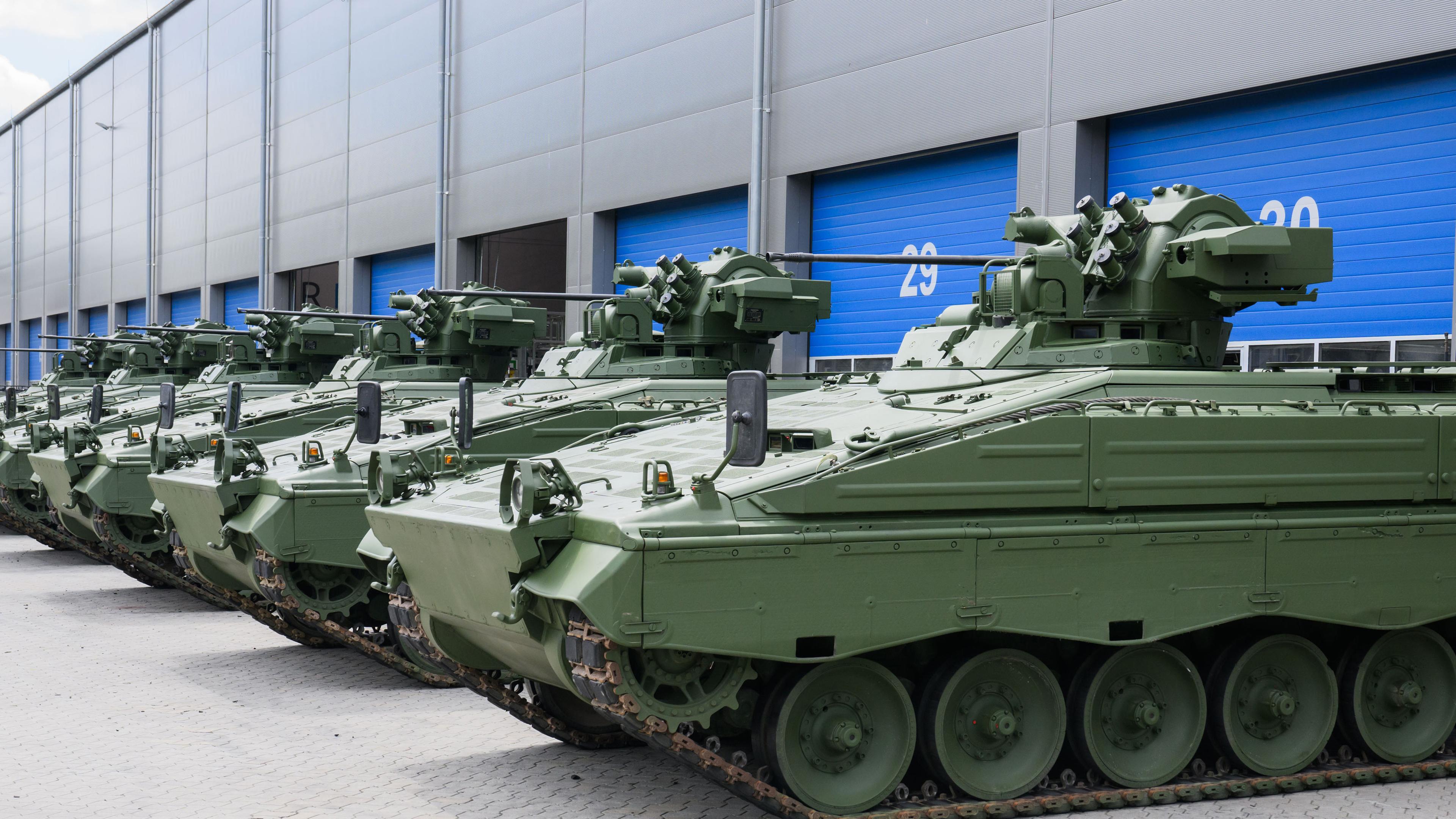 Wieder aufbereiteten Marder-Schützenpanzer stehen bei einer Führung durch das Rheinmetall-Werk anlässlich der Sommerreise des niedersächsischen Wirtschaftsministers vor einer Halle.